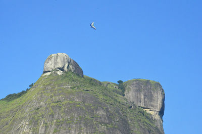 Low angle view of rocks against clear blue sky