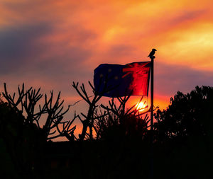 Low angle view of silhouette flag against sky during sunset