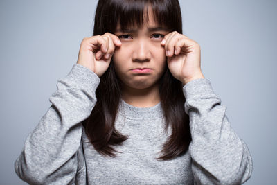 Sad young woman against gray background