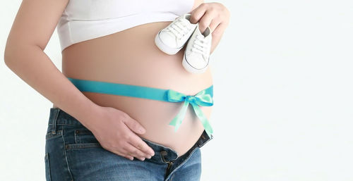 Midsection of woman standing against white background