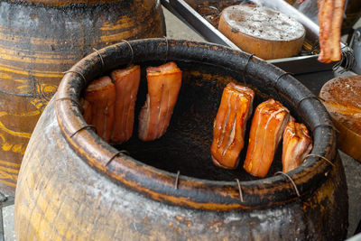 Roast pork belly hanging in a bbq ceramic jar in an outdoor restaurant kitchen