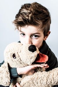 Portrait of boy with toy against gray background