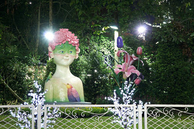 Statue against illuminated trees in park