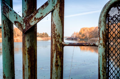 Rusty metal bridge over river against sky