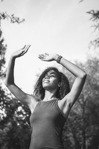 Low angle view of woman standing against trees against sky