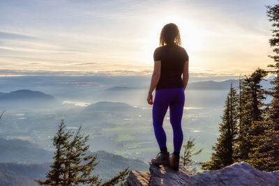 Rear view of man standing on mountain against sky