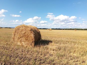 Hay bales on field against sky