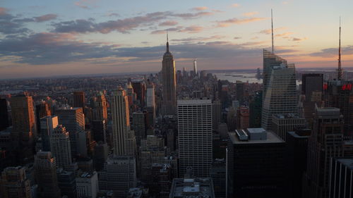 Modern buildings in city against sky during sunset