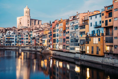 Buildings by river against sky in city
