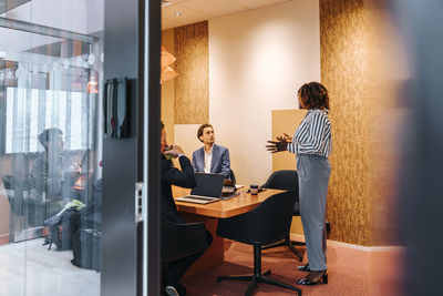 Side view of female entrepreneur planning strategies with colleagues in board meeting at office