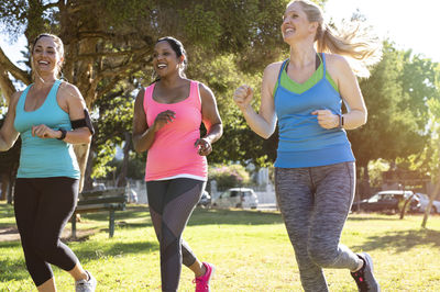 Low angle view of happy friends jogging on grassy field in park