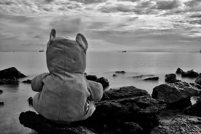 Rear view of rocks on beach against sky