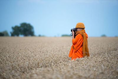 Rear view of woman standing on field against clear sky