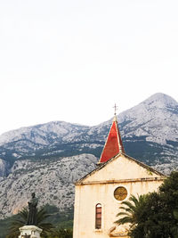 Temple against building and mountains against clear sky