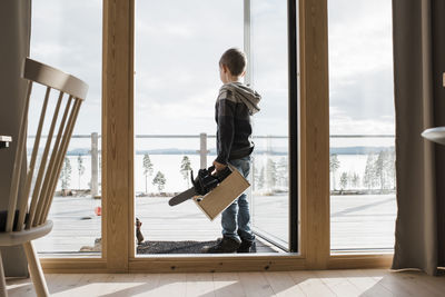 Side view of young man holding glass window