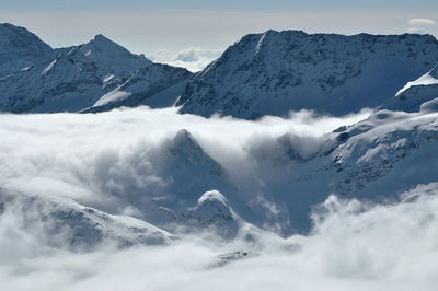 Snow covered high mountains, fog and clouds raising from above. alps, austria