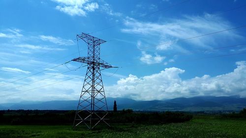 Low angle view of electricity pylon on field against sky