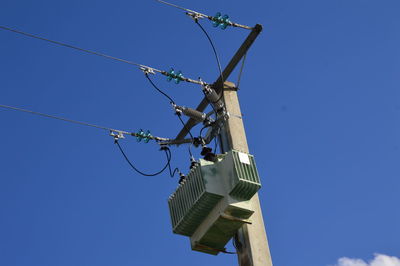 Low angle view of electricity pylon against clear blue sky