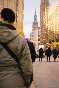 Rear view of people walking on street in city