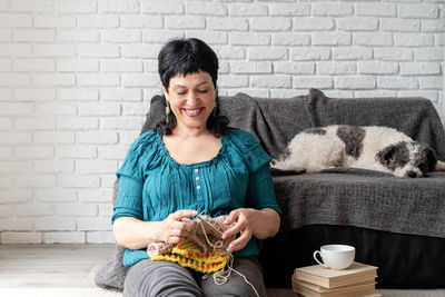 Smiling young woman sitting against wall