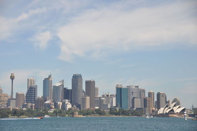 Sea by modern buildings against sky