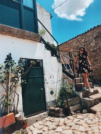 Low angle view of woman standing by building