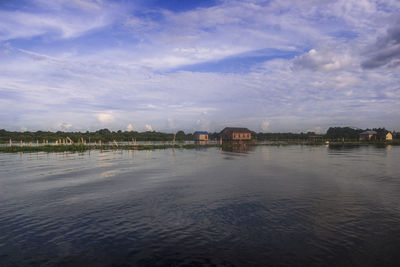 Scenic view of river by buildings against sky