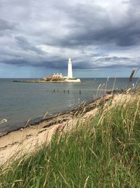 Lighthouse by sea against sky