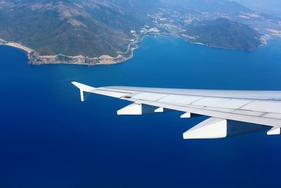 Cropped image airplane wing flying over sea