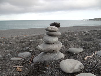 Stack of pebbles on beach against sky