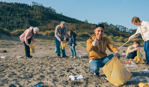 Portrait of man with family cleaning beach against mountain