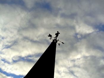 Low angle view of weather vane against cloudy sky