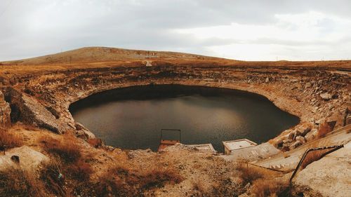 View of dam on mountain against cloudy sky