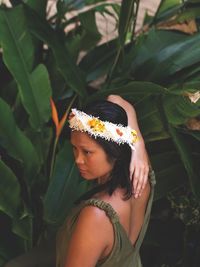 High angle view of thoughtful woman wearing flowers against plants