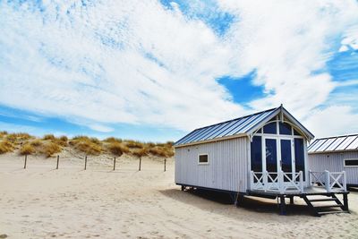 House on beach by buildings against sky