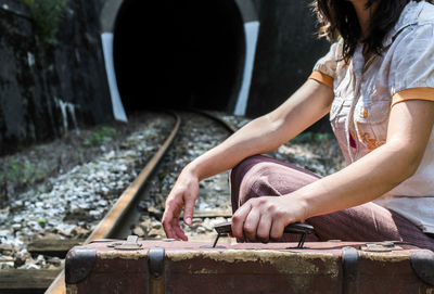 Side view of woman sitting on railroad track