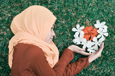 Optical illusion of woman holding flowers on grassy field