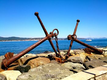 Close-up of rusty metal by sea against blue sky