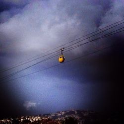 Low angle view of power lines against cloudy sky