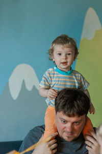 Portrait of cute baby girl playing with toys against blue background