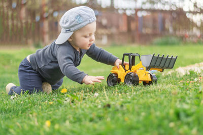 Baby boy playing with car on field