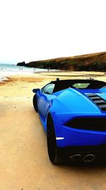 Car on beach against clear sky