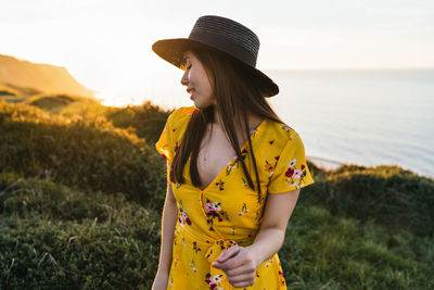 Woman looking away while standing on field against sky