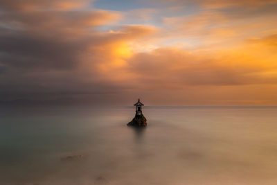 Rear view of man standing on beach against sky during sunset