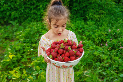 Surprised girl holding bowl of strawberries
