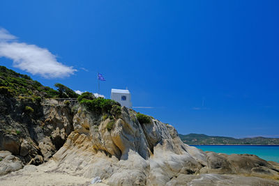 Built structure on rock against blue sky