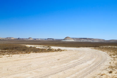 Scenic view of desert against clear blue sky