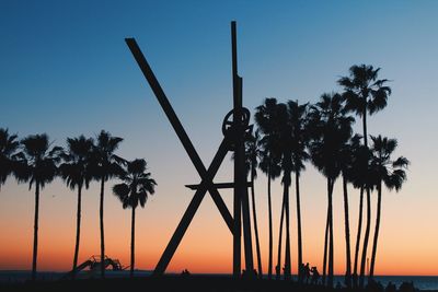 Silhouette of palm trees at beach during sunset