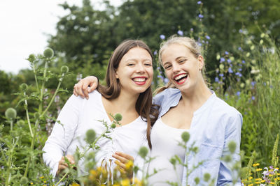 Portrait of a smiling young woman standing by plants on field