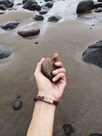 High angle view of hands on rocks at beach